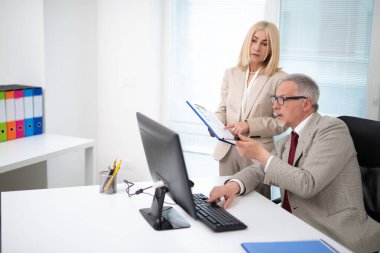 Parlak bir office belgesinde okunurken bir bilgisayarda çalışan iş adamları