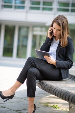 İş kadını tabletini kullanırken telefonda konuşuyor.