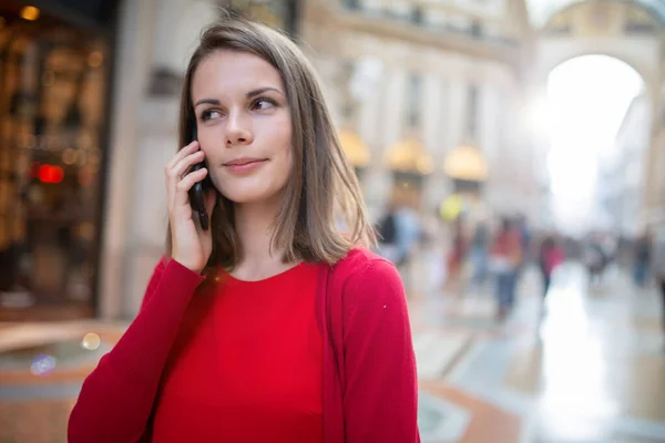 ヨーロッパの街を歩いている間に電話で話している若い女性 — ストック写真