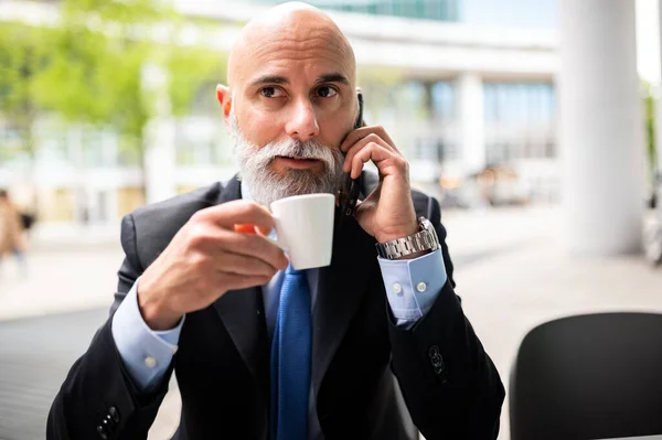 高级时尚秃头经理 留着白胡子 一边在户外一边打电话一边喝咖啡 — 图库照片
