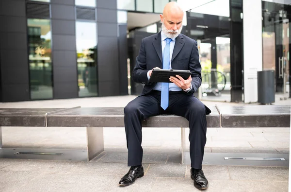 現代都市のベンチの屋外に座っている彼のタブレットを使用してスタイリッシュなマネージャー — ストック写真