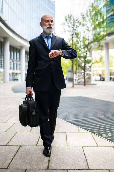 シニアスタイリッシュなはげビジネスマンは彼のバッグで歩く — ストック写真