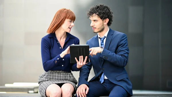 Dos Colegas Negocios Usando Una Tableta Aire Libre Sentados Banco —  Fotos de Stock