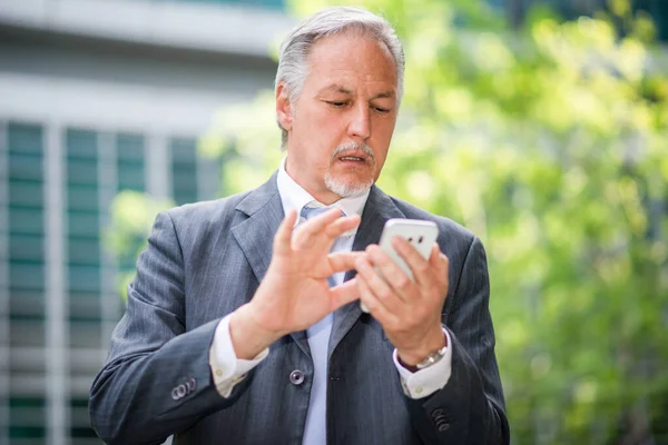 スマートフォンを屋外で使う上級実業家 — ストック写真