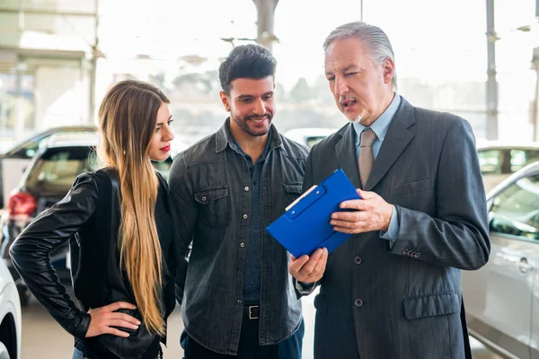 Happy Young Family Talking Salesman Choosing New Car Showroom — Stock Photo, Image