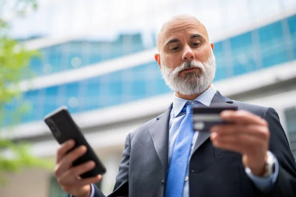 彼のクレジットカードと彼の携帯電話を使用してビジネスマン オンライン購入の概念 — ストック写真