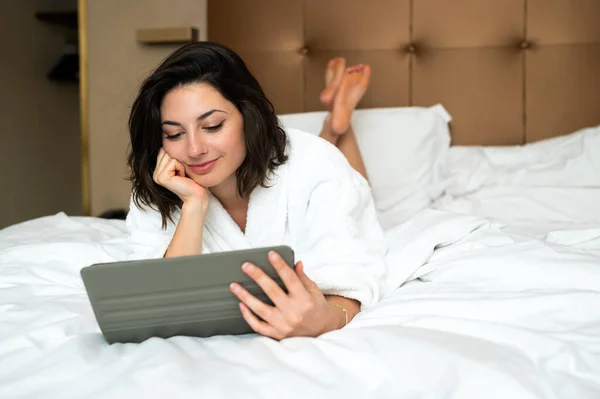 가운을 침대에 디지털 태블릿을 사용하는 아름다운 — 스톡 사진