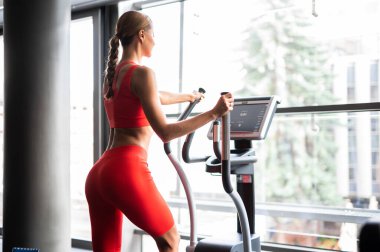 Woman exercising in a gym with an elliptical cross trainer