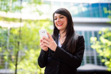 Güzel genç bayan yönetici dışarıda akıllı telefonunu kullanıyor.
