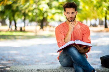 Yakışıklı genç adam parkta bankta kitap okuma