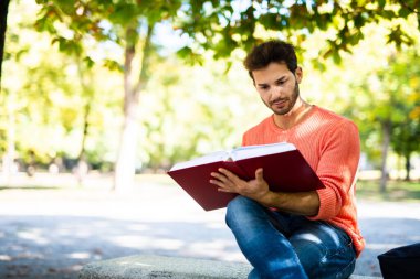 Yakışıklı genç adam parkta bankta kitap okuma
