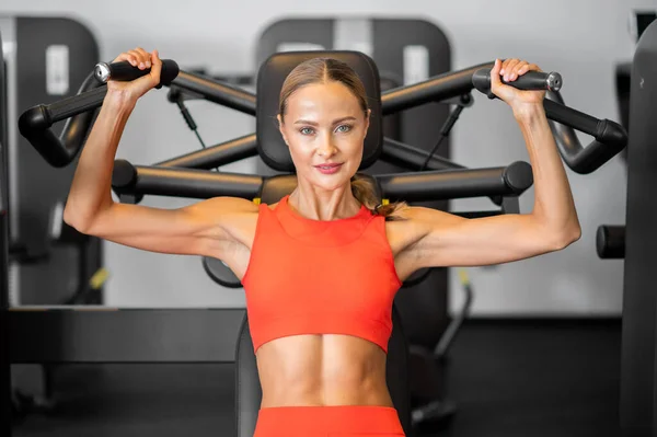 运动女子在健身房的机器上训练肩膀 — 图库照片