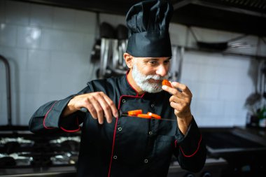 Profesyonel bir aşçı, bir restoranın mutfağında yemek tadıyor.