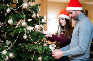 Mutlu çift birlikte Noel ağacı süslüyorlar.