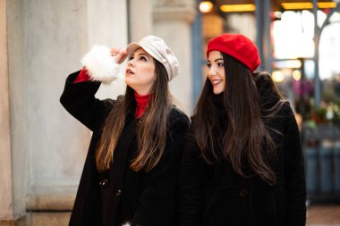 İki genç kadın gülümseyerek çekici şehirde alışveriş