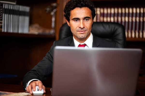 Профессиональный мужчина-руководитель, работающий на ноутбуке в хорошо оборудованной офисной среде