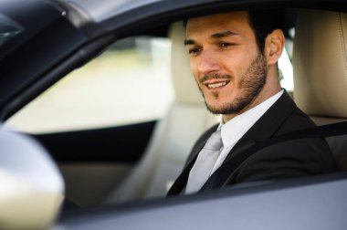 Üst düzey bir araç kullanırken gülümseyen profesyonel erkek yönetici.