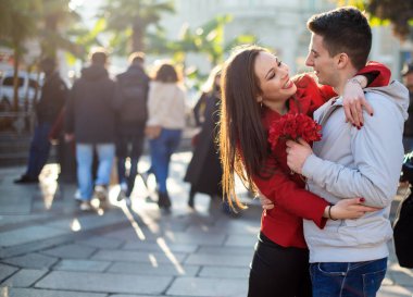 Young woman hugging her boyfriend because he gave her flowers - Valentine's Day concept
