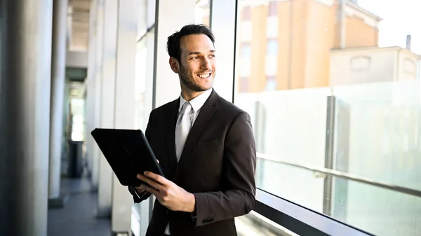 Cheerful male executive holding a digital tablet in a bright office environment