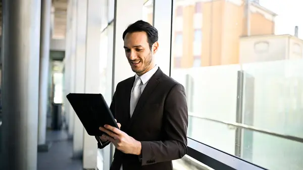 Well-dressed male executive working on a digital tablet in a modern urban setting