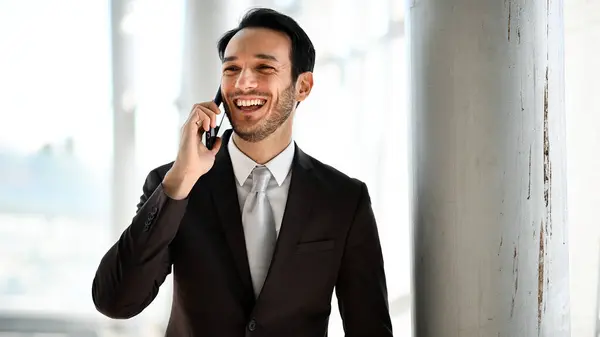 Smiling man in suit enjoys a conversation on his smartphone with natural light