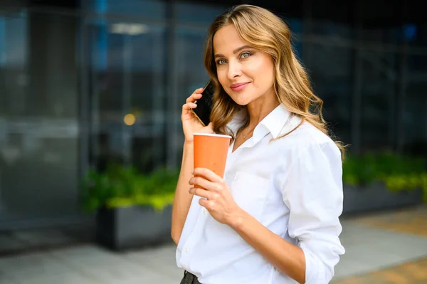 Woman White Shirt Talking Her Cell Phone While Holding Cup Stock Picture