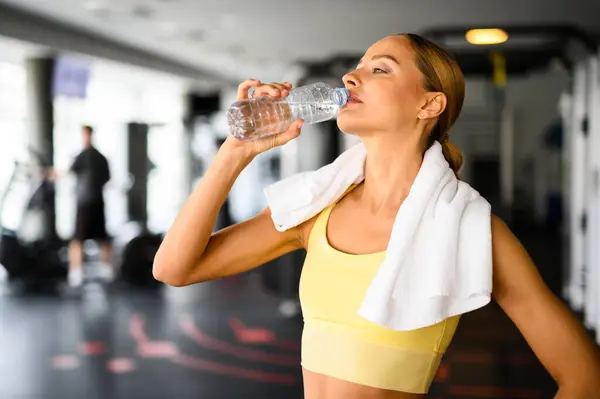 Jonge Vrouw Hydrateert Met Een Fles Water Sportschool Handdoek Haar Rechtenvrije Stockafbeeldingen