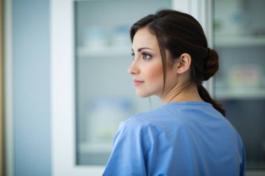 Thoughtful nurse in scrubs embodies healthcare professionalism, caring for patients with hope and dedication in a hospital room clipart