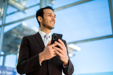 Neşeli erkek girişimci mesajları telefonunda. Parlak, çağdaş bir ofis içinde.