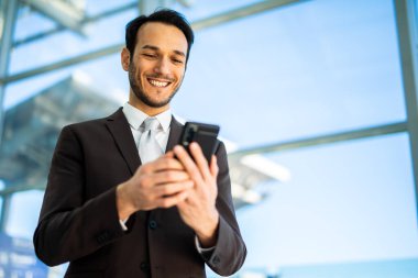 Kendine güvenen erkek girişimci, cam bina zeminiyle telefonunu kullanmaktan hoşlanıyor.