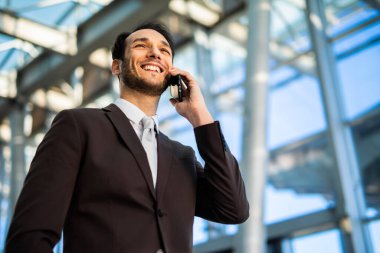 Kendine güvenen genç bir erkek profesyonel açık havada bir telefon görüşmesi yapıyor.