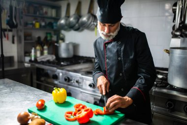 Odaklanmış şef, yoğun bir mutfakta taze sebzeleri dilimliyor, aşçılık becerileri ve profesyonelliği gösteriyor.