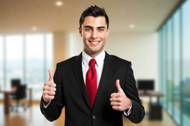 Modern ofisteki kendine güvenen genç işadamı, gülümseyen, başparmak kaldıran, başarı ve pozitiflik saçan. İş dünyasının lideri.