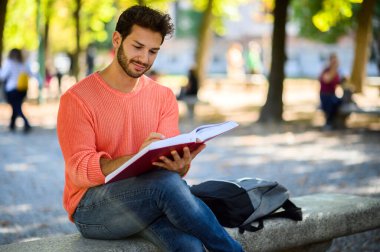 Yakışıklı genç adam parkta bankta kitap okuma
