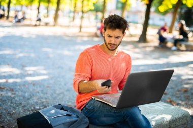 Odaklanmış erkek doğanın ortasında teknolojiyle uzaktan çalışır.