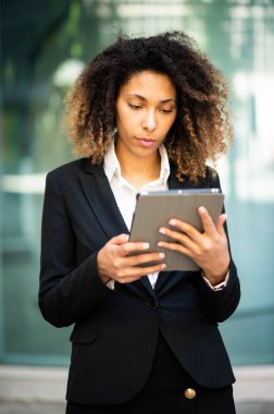 Gülümseyen Afro-Amerikan iş kadını dijital tablet kullanıyor.