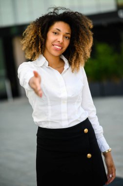 Kendine güvenen genç Afro-Amerikan bayan menajer size el sıkışıyor.