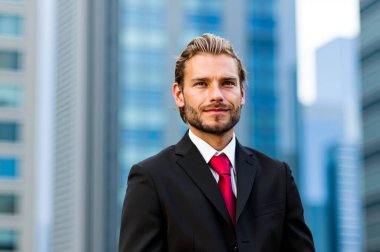 Takım elbiseli, kırmızı kravatlı, kendine güvenen genç bir işadamı, gülümsüyor ve şehir ortamını seyrediyor. Bulanık ofis binasının geçmişi şirket havası katıyor. Kariyerinde başarı ve hırs yayar.