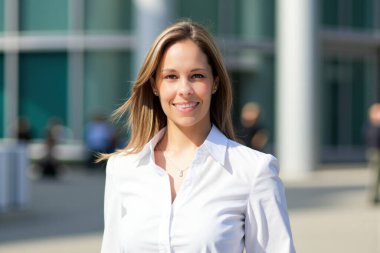 Ofis binasının önünde gülümseyen genç bir iş kadınının portresi.