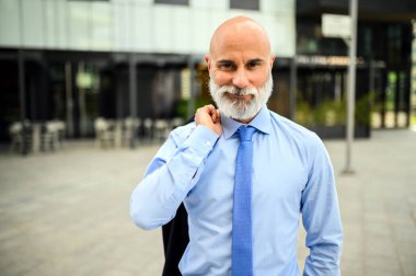 Kravatını düzelten sakallı kel bir iş adamının portresi.