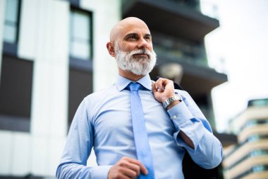 Ofisin dışında yürüyen kendinden emin, takım elbiseli, şehir arkaplanı, gülümseyen profesyonel lider, ilham verici kariyer başarıları.
