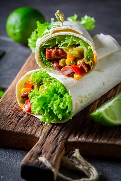 Spicy and hot burrito with red salsa and vegetables. Burrito with sausage and cheese served with sauce, vegetables and red salsa.