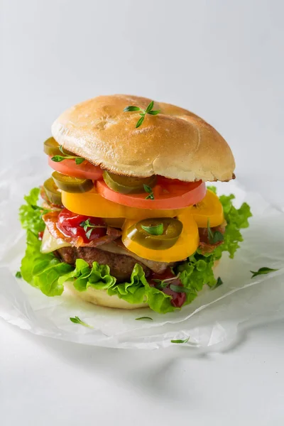 Tasty and fresh hamburger with bacon, tomato and beef on white paper