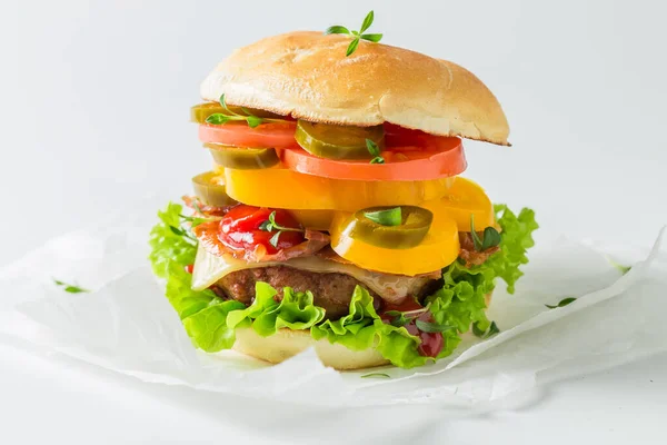 Hamburger with bacon, tomato and beef on white paper
