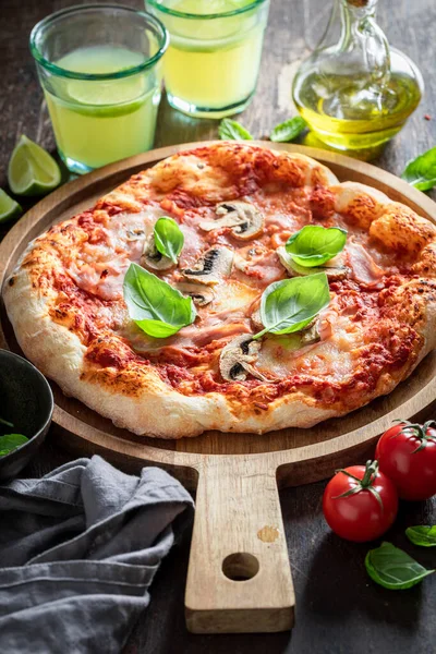 Homemade Capricciosa pizza with cheese, ham and mushrooms. Classic Italian cuisine. Capricciosa pizza with ham, cheese and mushrooms.