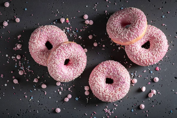 Homemade and sweet pink donuts with sprinkles and glaze. Donuts is most popular dessert.