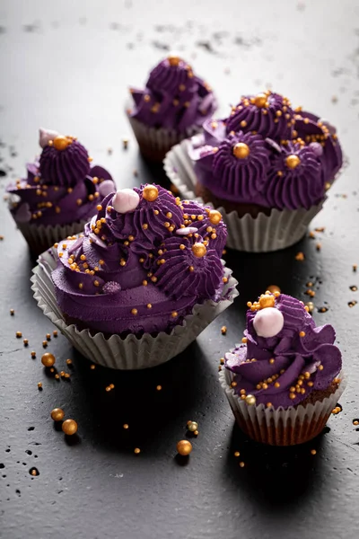 紫ホイップクリームと甘くおいしいカップケーキ 黄金のスプリンクルと紫のデザート — ストック写真