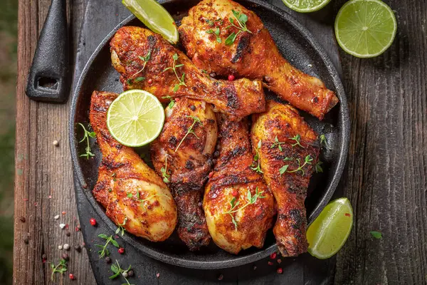 Hot roasted chicken leg served with sauces and lime. Grilled chicken leg with herbs and spicy spices.