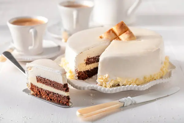Delicious white chocolate cake made white chocolate and brownie. White chocolate cake on white porcelain.