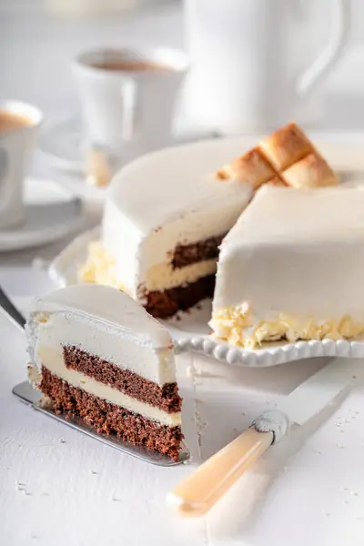 Sweet white chocolate cake with gold chocolate and glaze. White chocolate cake on white porcelain.